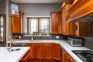 Kitchen with gas stovetop, wood finish cabinetry, dark wood finished floors, and decorative light fixtures