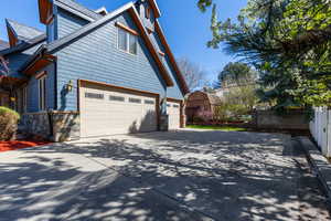 View of side of property featuring concrete driveway, a garage, and stone siding