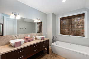 Full bathroom featuring double vanity and a soaking tub
