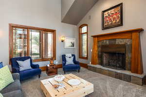 Living area with a tile fireplace, vaulted ceiling, and carpet flooring