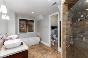 Bathroom featuring a shower stall, double vanity, a bidet, stone finish flooring, and a freestanding bath