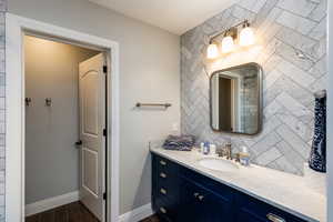 Bathroom featuring vanity, decorative backsplash, and wood finish floors