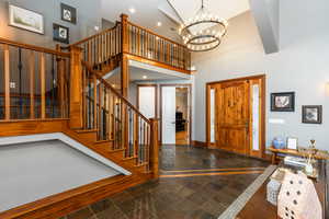 Foyer with stone tile floors, hanging lights, and a high ceiling