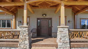 Entrance to property with stucco siding, covered porch, and stone siding