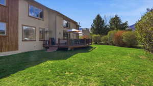 View of green lawn featuring a wooden deck