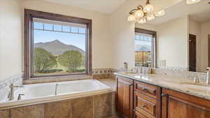 Full bath with double vanity, a mountain view, hanging lights, and a garden tub