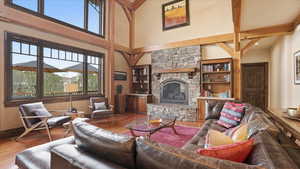 Living area with a fireplace, wood finished floors, built in features, and a high ceiling