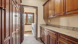 Laundry area featuring washer / dryer and light stone finish flooring