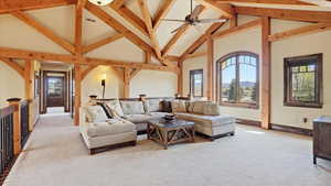 Living area featuring a high ceiling, light colored carpet, and a ceiling fan