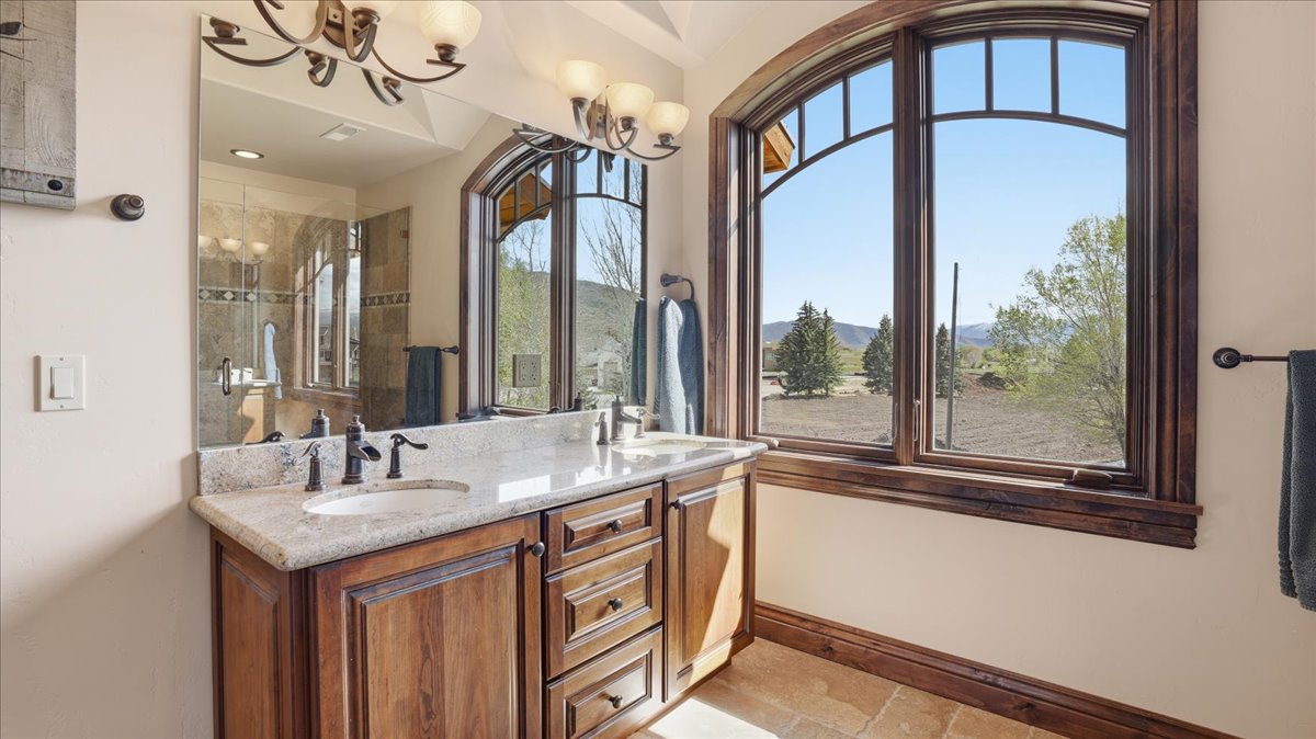 Bathroom featuring double vanity, stone tile floors, a mountain view, a tile shower, and a chandelier