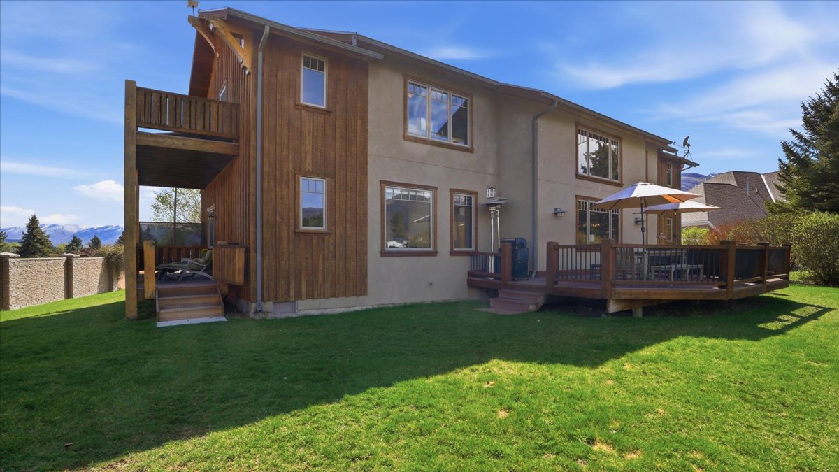 Rear view of house featuring a wooden deck and a lawn