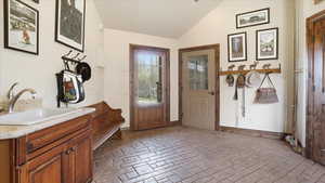 Foyer entrance featuring lofted ceiling and brick floors