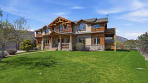 View of front of home featuring covered porch, a front lawn, stone siding, and stucco siding