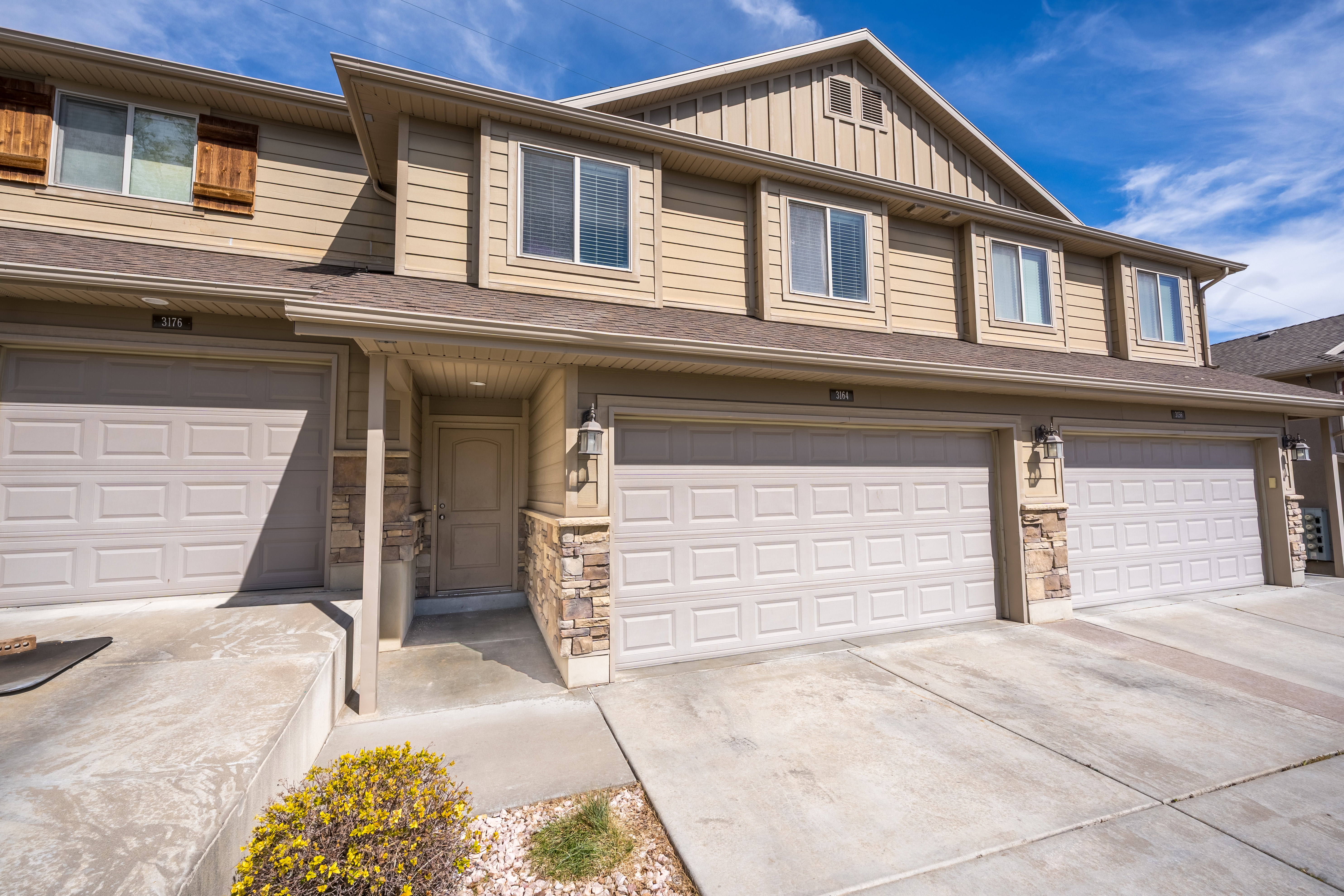 View of front facade with stone siding, board and batten siding, an attached garage, concrete driveway, and roof with shingles