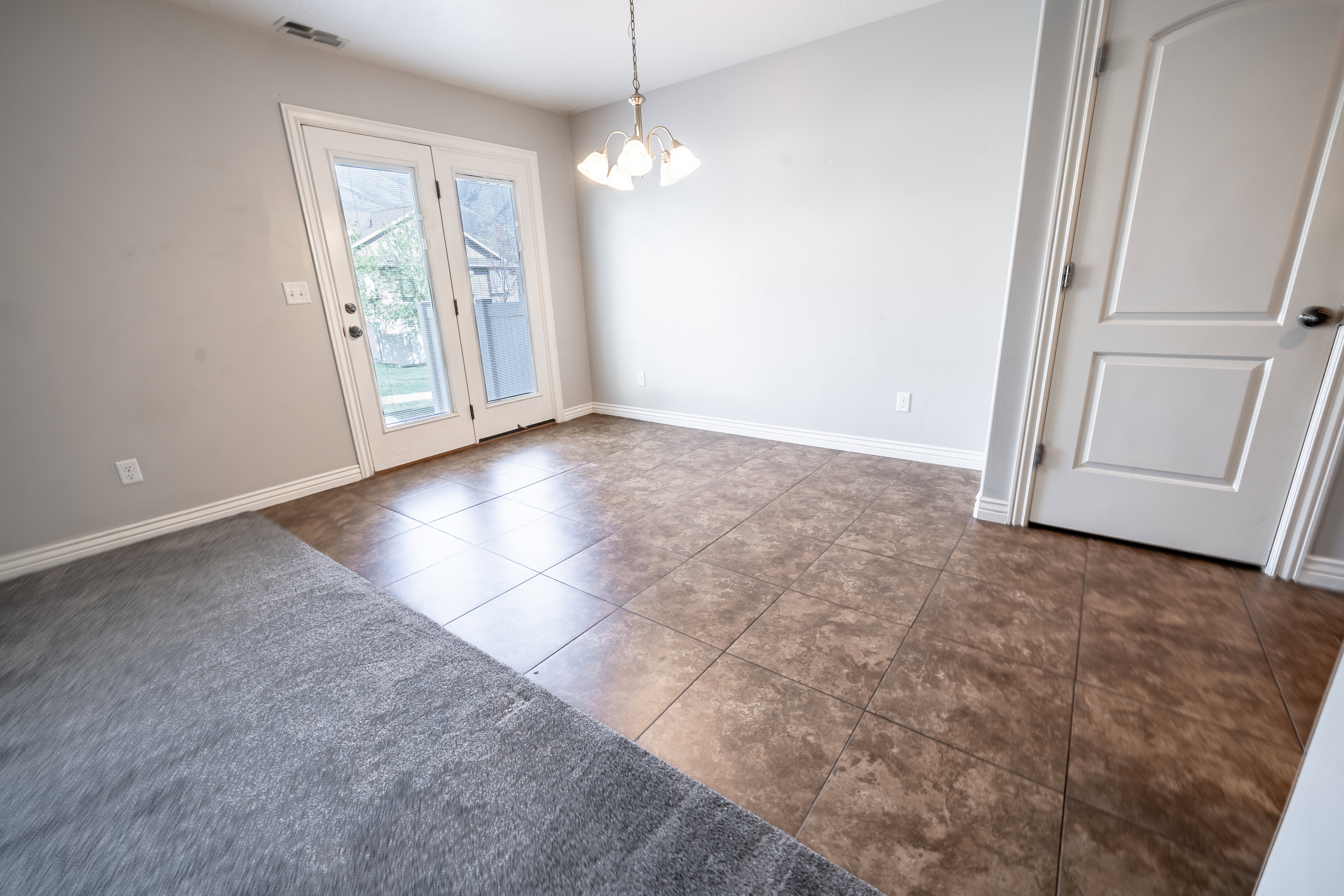 Unfurnished dining area featuring hanging lights and dark tile patterned flooring
