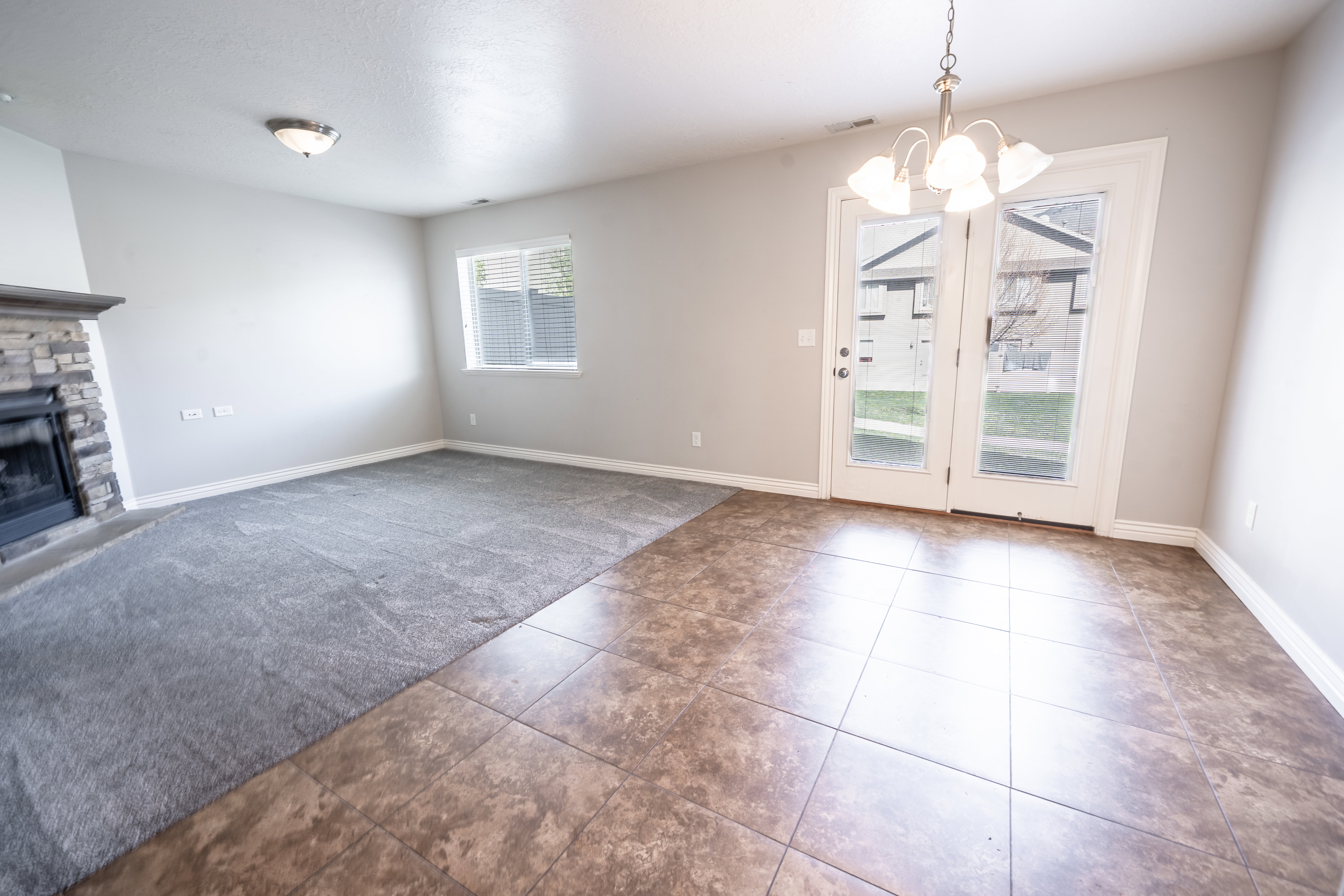 Unfurnished living room featuring dark tile patterned floors, a fireplace, and hanging lights