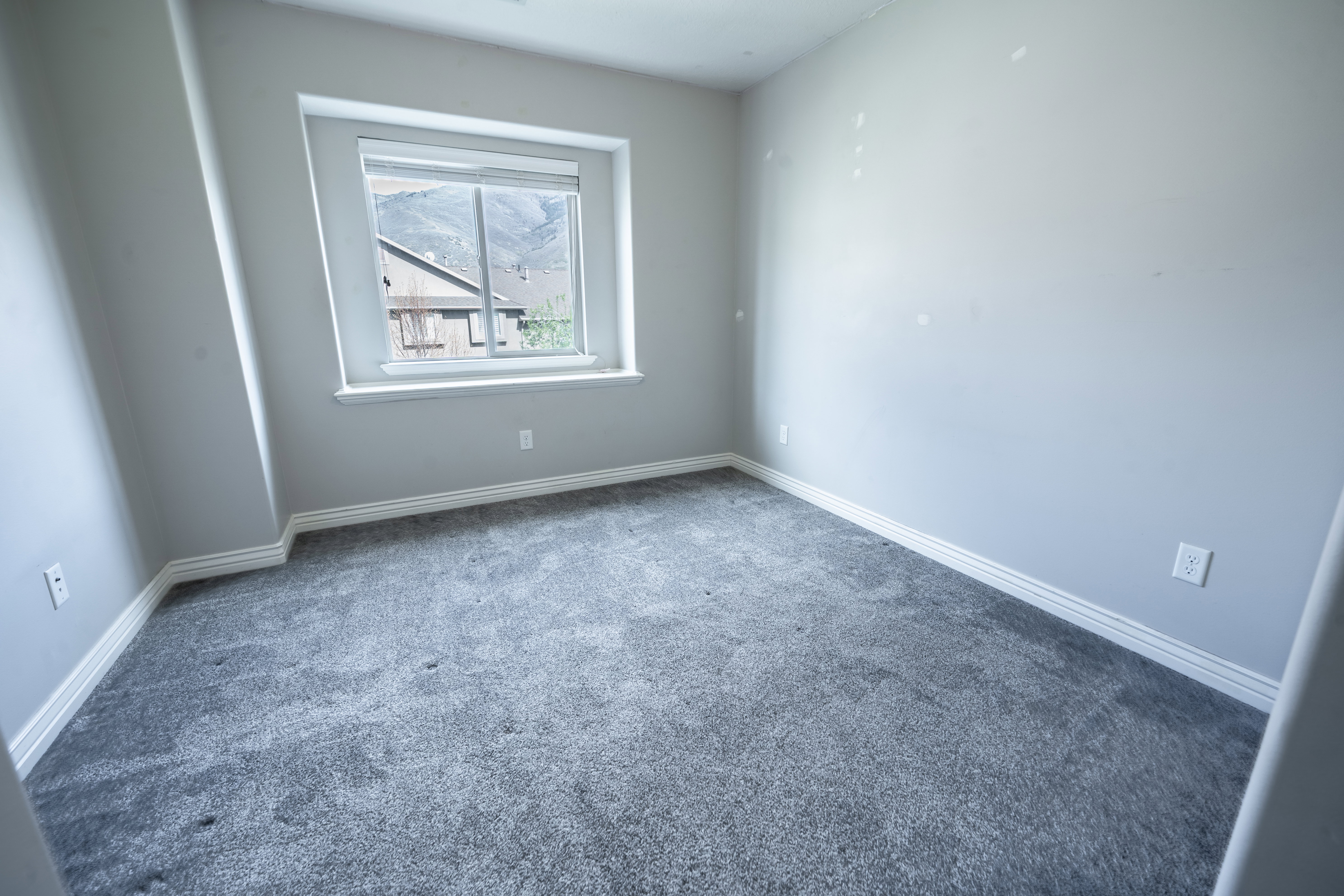 Spare room featuring dark colored carpet and baseboards