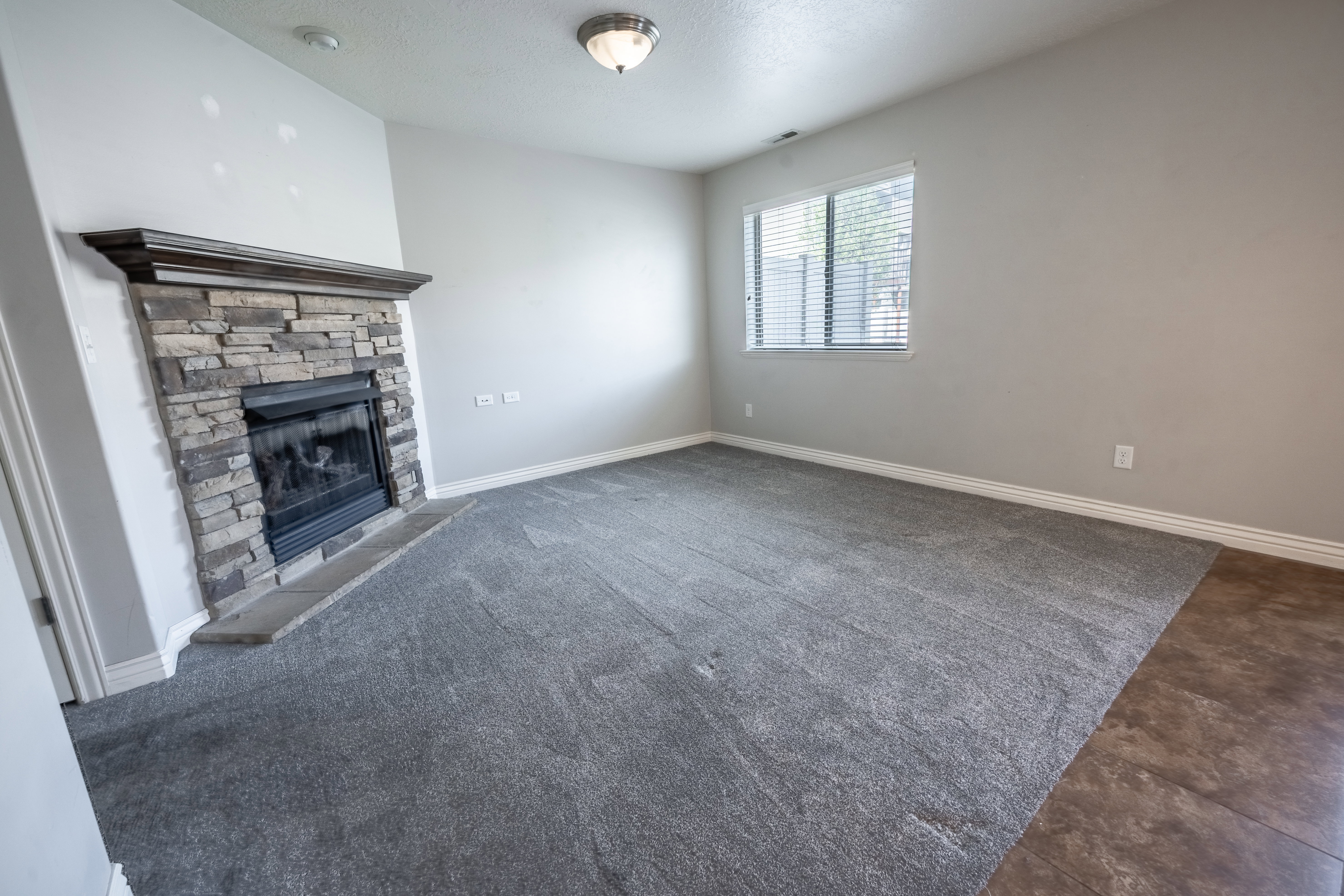 Unfurnished living room featuring a stone fireplace and a textured ceiling