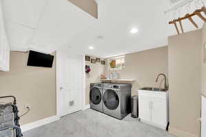 Laundry area featuring washing machine and dryer, recessed lighting, cabinet space, and light marble finish floors