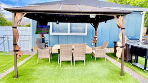 Outdoor gazebo with a hardtop roof and privacy curtains, set on artificial turf
