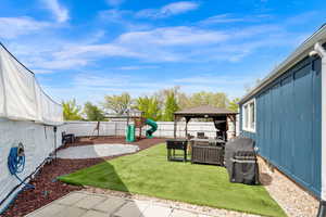 Fenced backyard featuring a patio area, a gazebo, and a playground