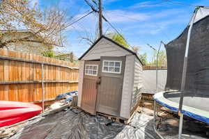 View of shed featuring a fenced backyard and a trampoline
