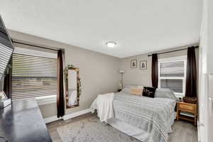 Bedroom with light wood-type flooring and a textured ceiling
