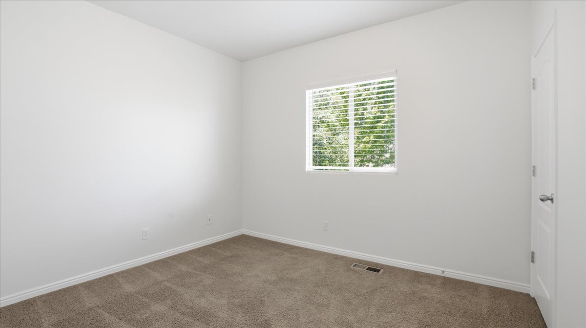 Neutral wall paint, plush carpet flooring, baseboard trim, and a window with horizontal blinds