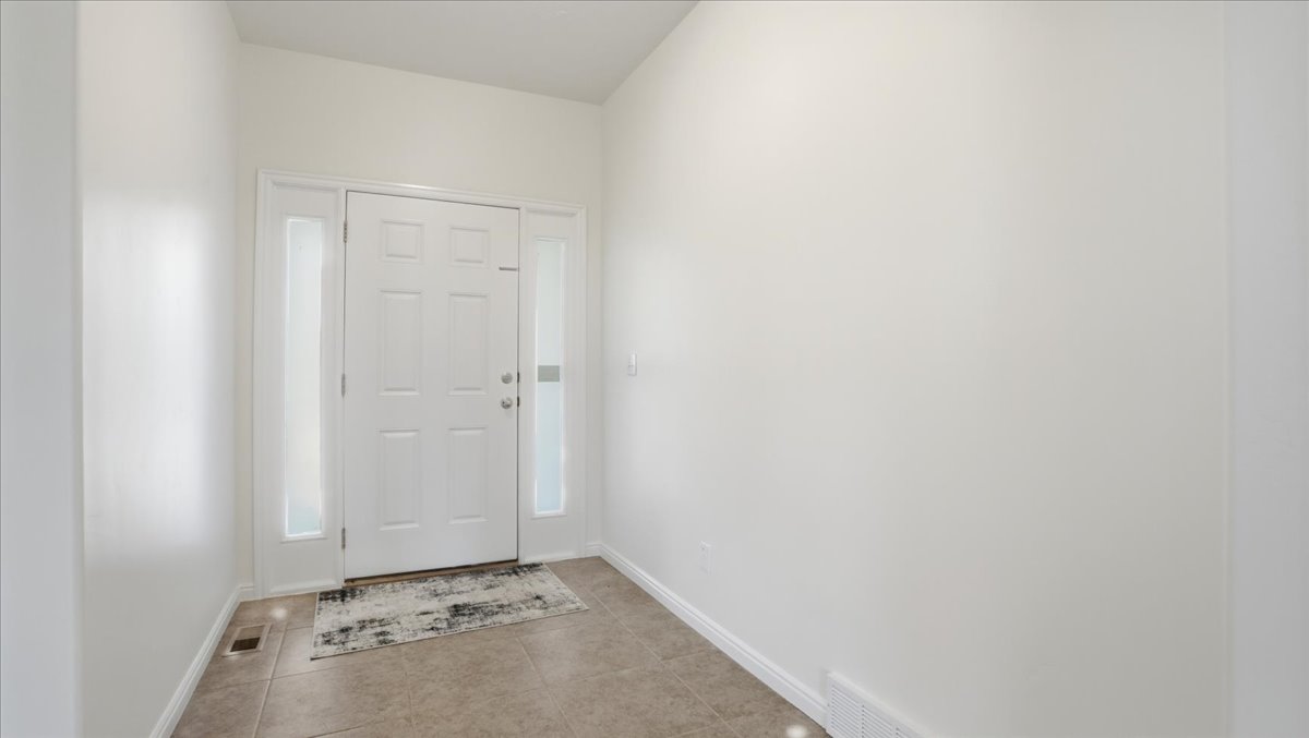 Foyer featuring a paneled entry door with sidelights, neutral wall tones, and tiled flooring