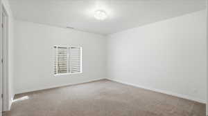 Empty room with light colored carpet and baseboards