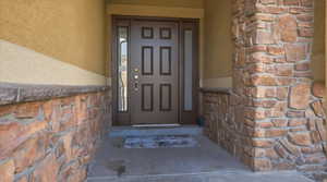 View of exterior entry with stone siding and stucco siding