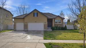 Traditional home with a garage, concrete driveway, stucco siding, stone siding, and a tiled roof