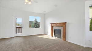 Unfurnished living room with carpet flooring, ceiling fan, and a tile fireplace