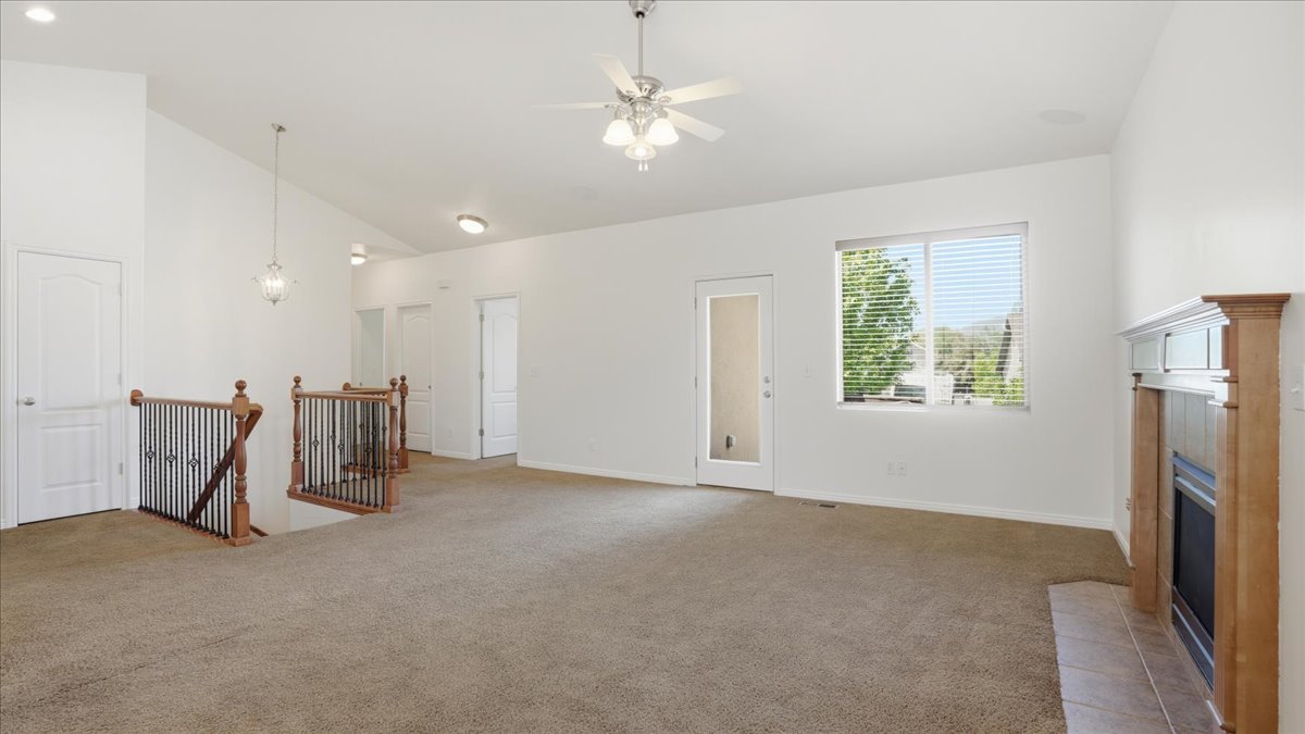 Spacious room featuring vaulted ceilings and neutral carpeting