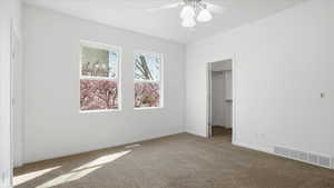 Unfurnished bedroom with a spacious closet, carpet flooring, and ceiling fan