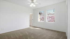 Carpeted spare room featuring baseboards and ceiling fan