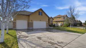 Traditional-style home featuring a garage, driveway, a tiled roof, stucco siding, and stone siding