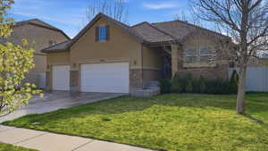 Traditional home with stone siding, stucco siding, a garage, concrete driveway, and a tiled roof