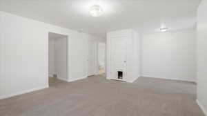 Empty room featuring light colored carpet and a textured ceiling