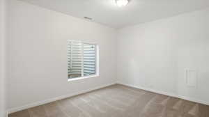 Unfurnished room featuring baseboards and light carpet