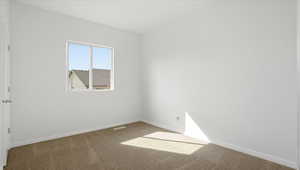 Spare room featuring light colored carpet and baseboards