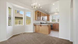 Kitchen featuring a peninsula, glass fronted cabinets, a breakfast bar, light colored carpet, and wood finish cabinets