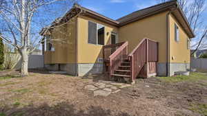 Rear view of house featuring stucco siding and stairway