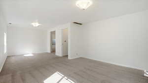 Empty room with light colored carpet and baseboards