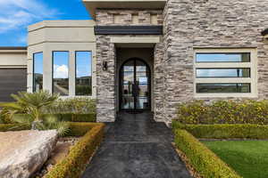 Entrance to property featuring stone siding, french doors, and stucco siding