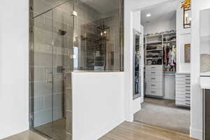 Bathroom featuring light wood-style flooring, a stall shower, a walk in closet, and vanity