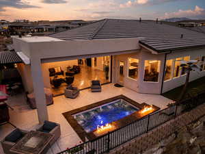 Back of house at dusk featuring stucco siding, a patio, outdoor lounge area, and a fire pit