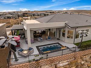 Back of property with stucco siding, a patio, an outdoor living space with a fire pit, and a fenced backyard