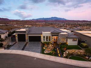 Prairie-style house featuring stone siding, a garage, a mountain view, driveway, and stucco siding