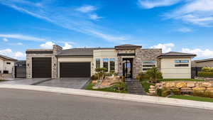 Prairie-style house with stone siding, an attached garage, asphalt driveway, stucco siding, and a tile roof